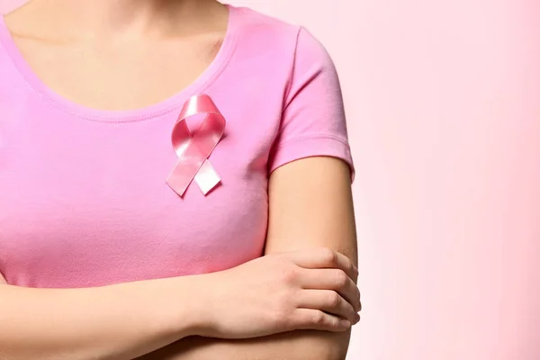 Mujer con cinta rosa en camiseta sobre fondo de color. Concepto de conciencia sobre el cáncer de mama —  Fotos de Stock