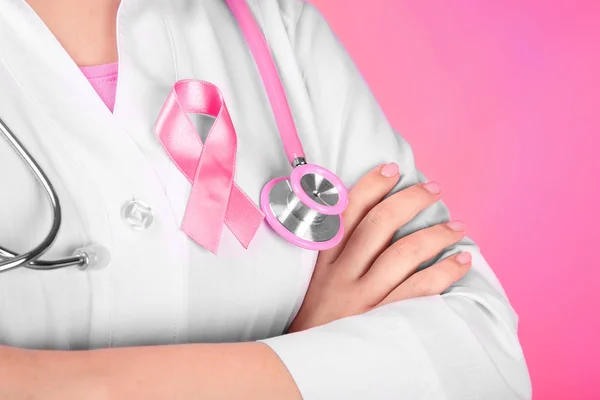 Läkare med rosa bandet på mantel mot färgbakgrund. Breast cancer awareness koncept — Stockfoto