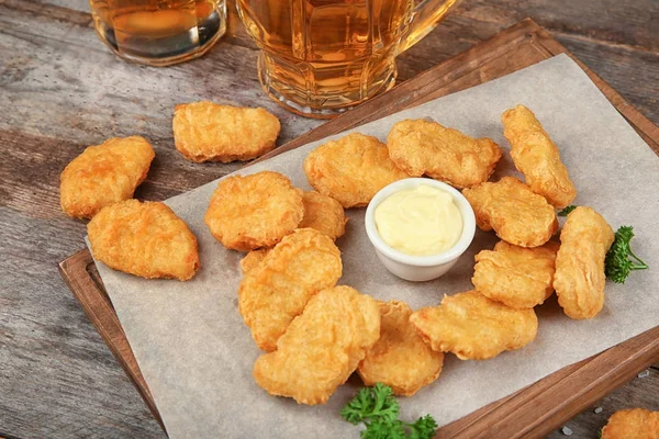 Holzbrett mit leckeren Chicken Nuggets und Soße auf dem Tisch — Stockfoto