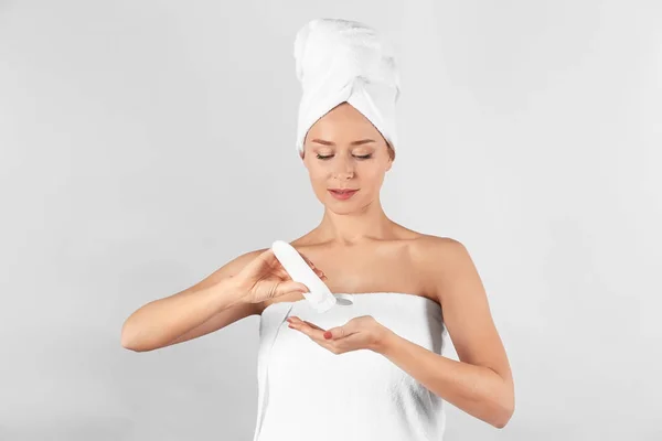 Young woman applying body cream on light background — Stock Photo, Image