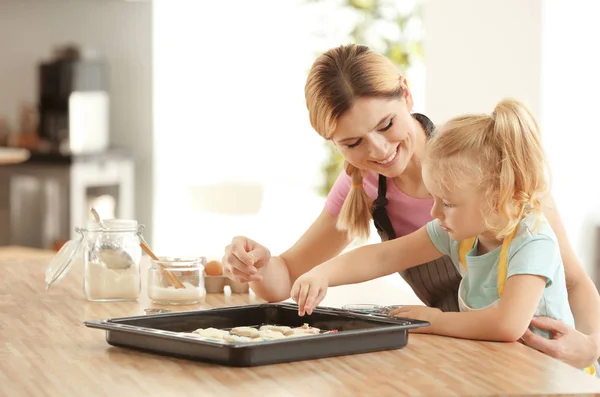 Mother and daughter decorating cookie dough with sprinkles indoors — Stock Photo, Image