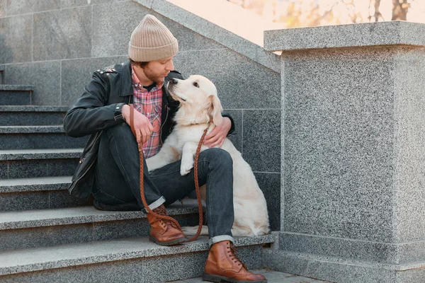 Handsome young hipster with dog outdoors — Stock Photo, Image