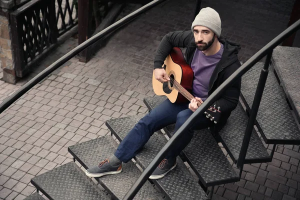 Hipster młody mężczyzna gra na gitarze na zewnątrz — Zdjęcie stockowe