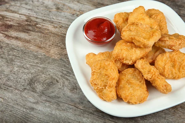 Plate with tasty chicken nuggets and sauce on table — Stock Photo, Image