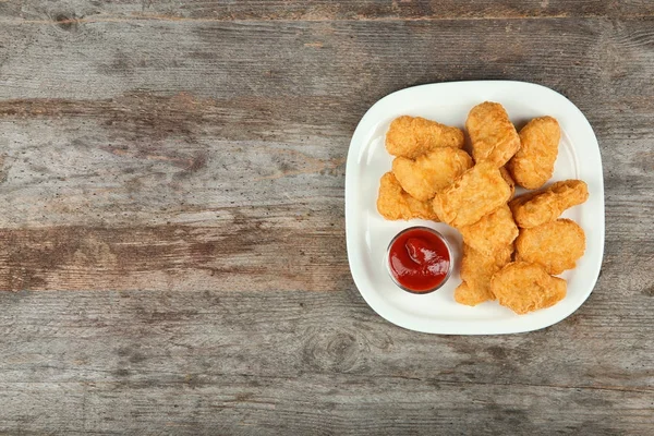 Teller mit leckeren Chicken Nuggets und Soße auf dem Tisch — Stockfoto