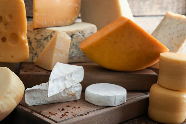 Träskiva med olika sorters läckra ost på bordet — Stockfoto