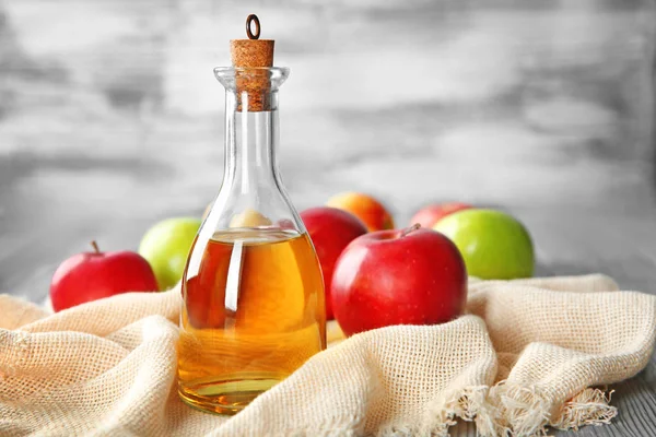Bottiglia di vetro con aceto di mele e frutta fresca in tavola — Foto Stock