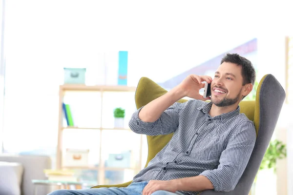 Knappe Jonge Man Praten Telefoon Zittend Een Comfortabele Fauteuil Thuis — Stockfoto