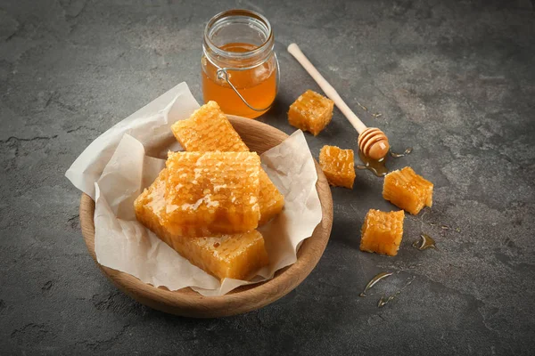 Μπολ με γλυκό κηρήθρες και βάζο με μέλι σε γκρίζο φόντο — Φωτογραφία Αρχείου