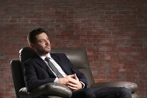 Hombre Negocios Guapo Sentado Cómodo Sillón Sobre Fondo Pared Ladrillo —  Fotos de Stock