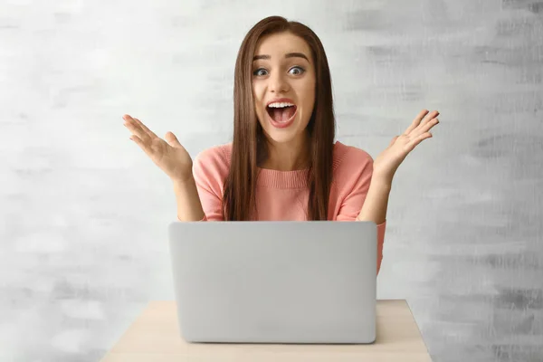 Jovem mulher emocional com laptop no fundo de luz — Fotografia de Stock