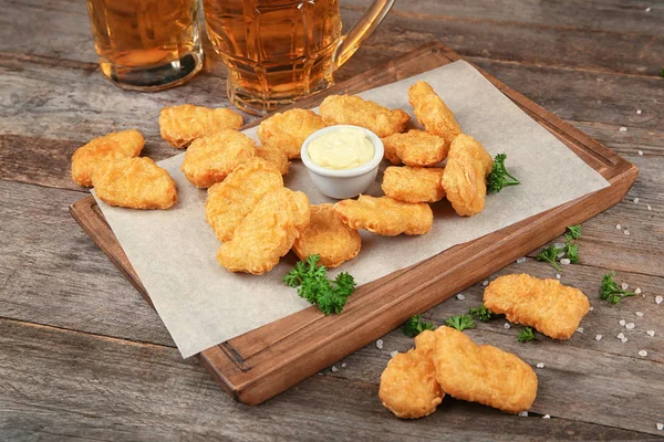 Holzbrett mit leckeren Chicken Nuggets und Soße auf dem Tisch — Stockfoto