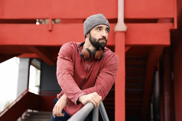 Portret van jonge hipster man met hoofdtelefoon buitenshuis — Stockfoto