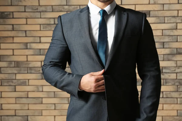 Handsome man in formal suit against brick wall, closeup — Stock Photo, Image