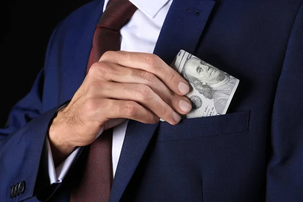 Businessman putting money in pocket, closeup. Corruption concept