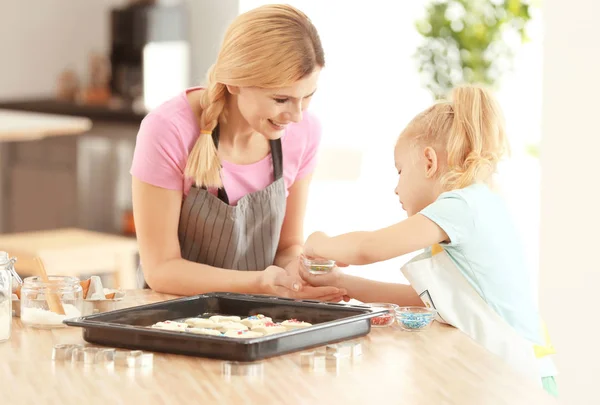 Mãe e filha decorando massa de biscoito com polvilhas dentro de casa — Fotografia de Stock