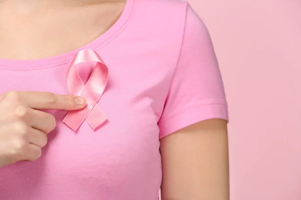 Mujer mostrando cinta rosa sobre fondo de color. Concepto de conciencia sobre el cáncer de mama — Foto de Stock