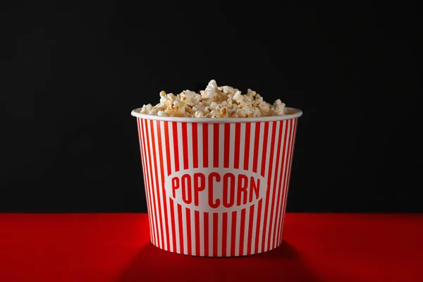 Randig Hink Med Läckra Popcorn Bordet Mot Mörk Bakgrund — Stockfoto