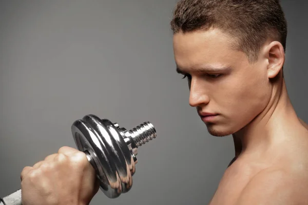 Muskulöser Junger Bodybuilder Mit Hantel Auf Grauem Hintergrund — Stockfoto