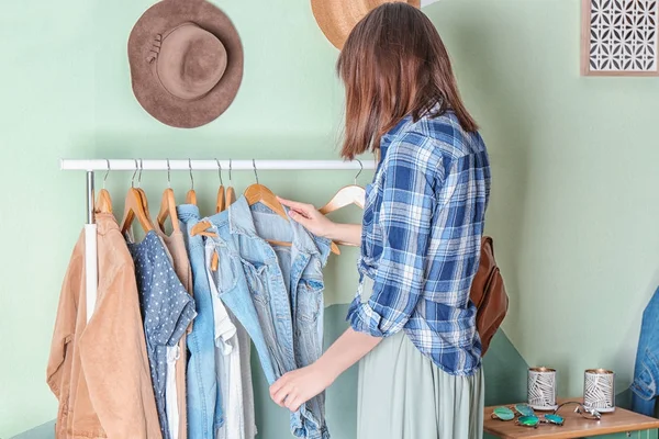 Woman choosing clothes on rack in dressing room — Stock Photo, Image