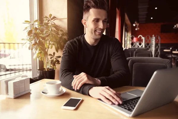 Joven hombre hipster con café y portátil en la cafetería — Foto de Stock