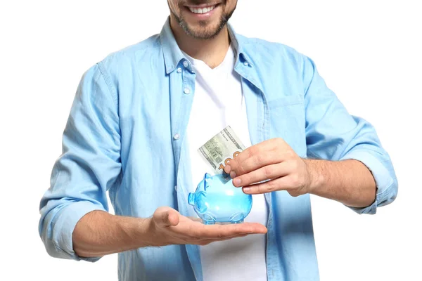 Hombre poniendo dinero en alcancía sobre fondo blanco — Foto de Stock