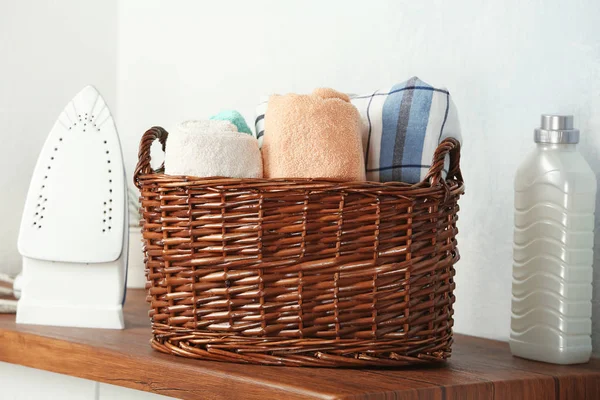 Korb mit Wäsche, Bügeleisen und Waschmittel auf Holztisch — Stockfoto