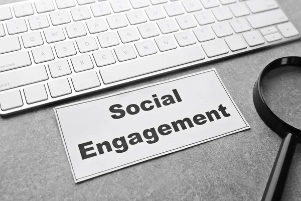 Έγγραφο με το κείμενο το Social Engagement κοντά στο πληκτρολόγιο και τον μεγεθυντικό φακό στο γραφείο τραπέζι — Φωτογραφία Αρχείου