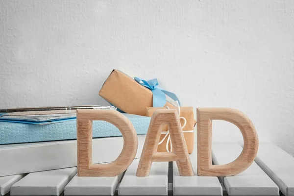 Word "Dad" made of wooden letters and gift boxes on table. Father's Day celebration — Stock Photo, Image