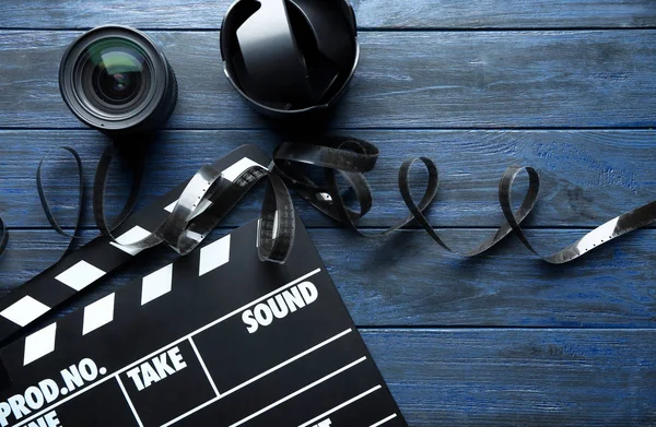 Movie clapper, filmstrip and lenses on wooden background, top view — Stock Photo, Image