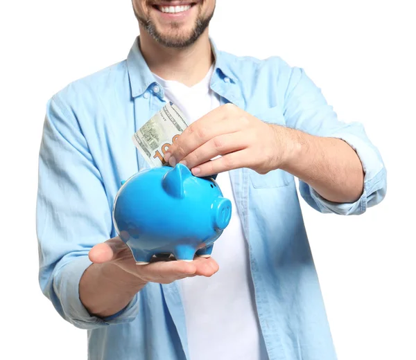 Man putting money into piggy bank on white background — Stock Photo, Image