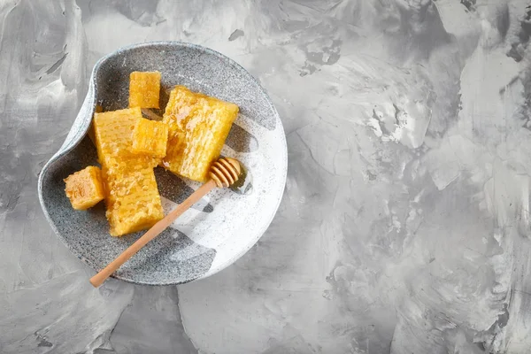 Plate with honeycombs and wooden dipper on grey background — Stock Photo, Image