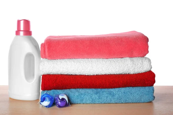 Folded towels and laundry detergent on table against white background — Stock Photo, Image