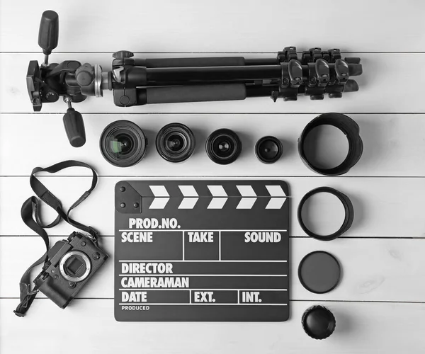 Composition with movie clapper, tripod, camera and different lenses on light background, top view — Stock Photo, Image