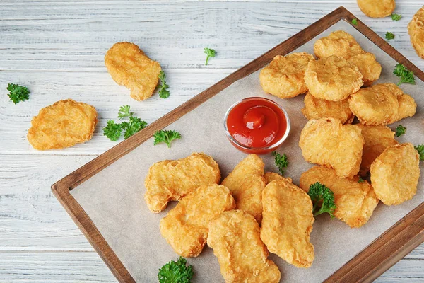 Deska z tasty chicken nuggets i sosem na stole — Zdjęcie stockowe