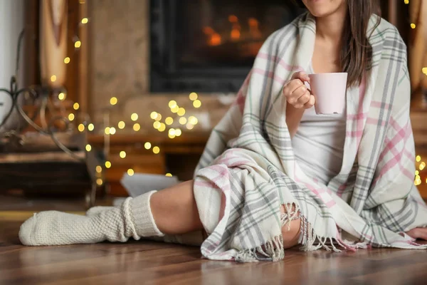 Νεαρή Γυναίκα Χαλάρωσης Πίνοντας Τσάι Στο Σαλόνι Διακοσμημένο Για Χειμερινές — Φωτογραφία Αρχείου