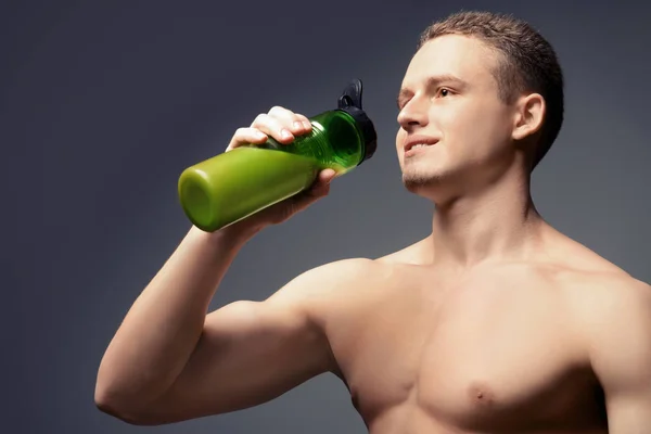 Muskulöser Junger Bodybuilder Mit Einer Flasche Proteincocktail Auf Grauem Hintergrund — Stockfoto