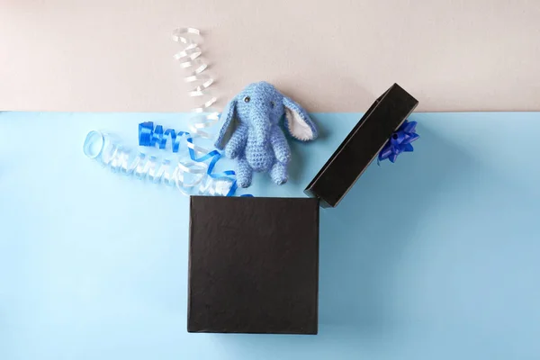 Geöffnete Geschenkschachtel mit handgemachtem Spielzeug und Luftschlangen auf farbigem Hintergrund, Ansicht von oben — Stockfoto