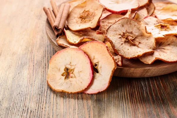 Houten plaat met smakelijke apple chips op tafel — Stockfoto