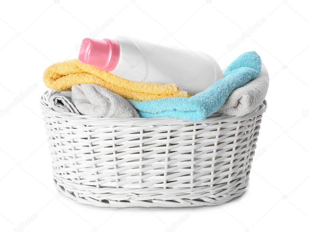 Basket with folded towels and laundry detergent on white background