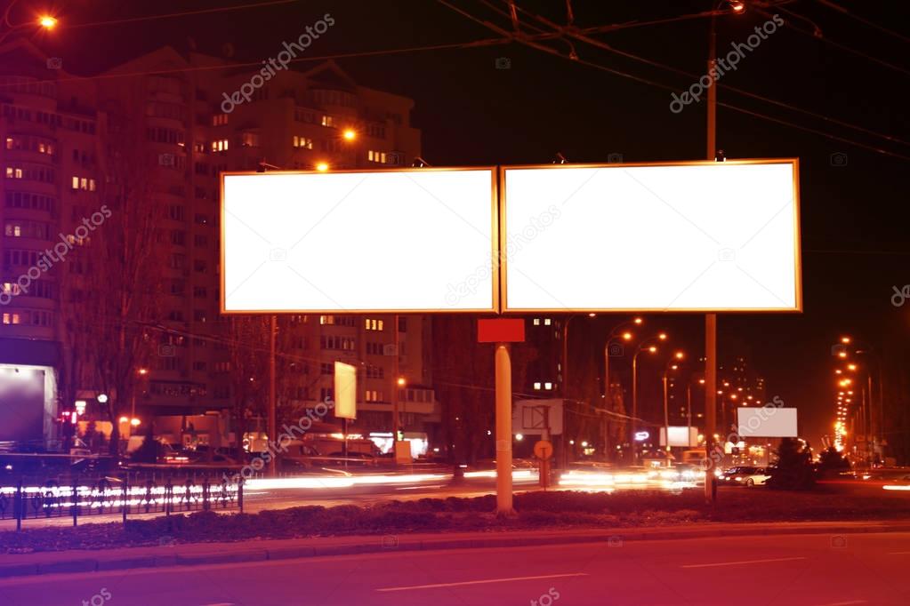 Blank advertising boards on city street at night