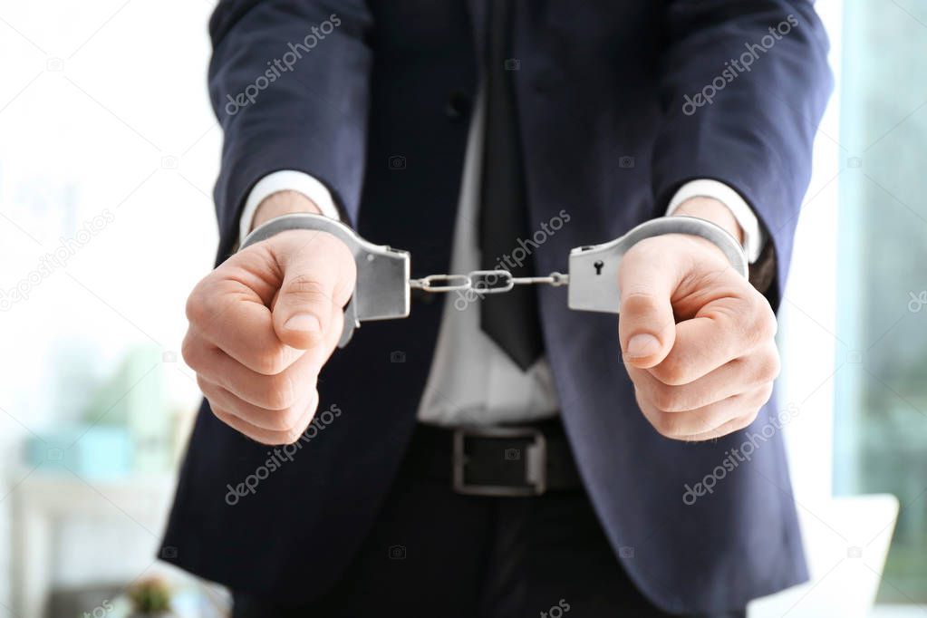 Businessman in handcuffs on blurred background
