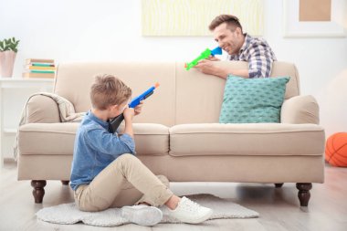 Sevimli çocuk ve babası evde oyuncak silahlarla oynayan