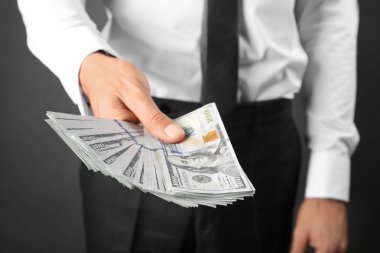 Para koyu arka plan üzerinde tutan bir iş adamı. Yolsuzluk kavramı
