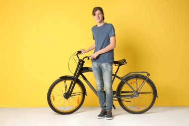 Hipster genç sarı arka plan üzerinde bisiklet ile