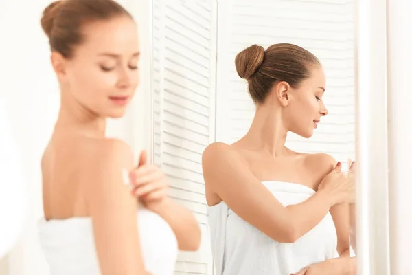 Giovane donna che applica crema per il corpo in bagno — Foto Stock