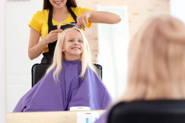 Femme coiffeuse travaillant avec une petite fille dans le salon — Photo