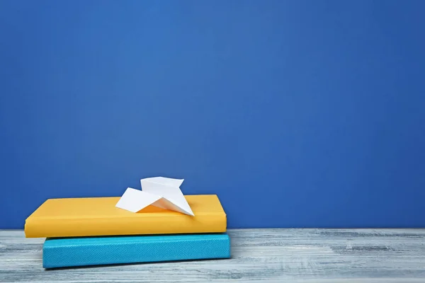 Books and paper plane on table against color background. Doing homework