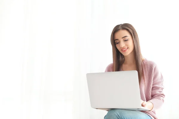 Mujer joven con portátil moderno en el fondo de luz — Foto de Stock