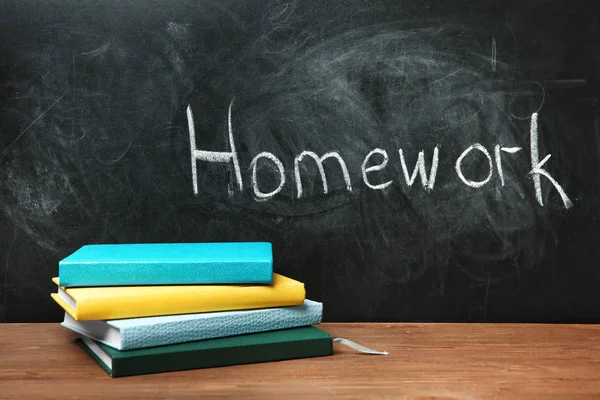 Notizbücher Auf Tisch Neben Tafel Mit Dem Wort Hausaufgaben — Stockfoto